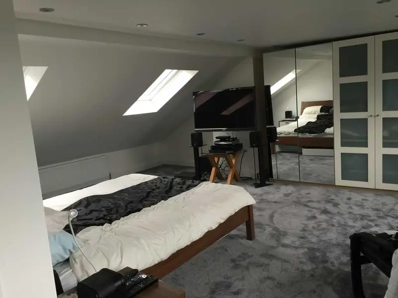 Loft bedroom with a rooflight in the sloping ceiling, grey carpet and mirrored fitted wardrobes
