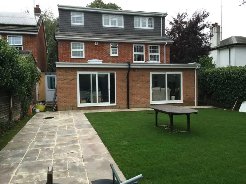 Finished brick rear extension with two sets of glazed doors opening onto a new stone patio and lawn