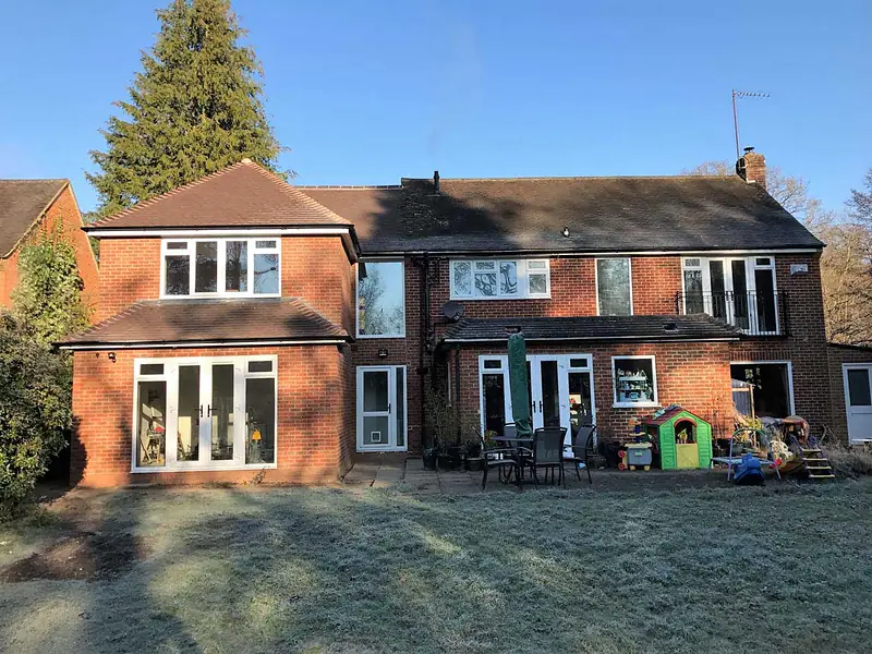 Two-storey brick extension with French doors on a detached house, seen across a frosty lawn